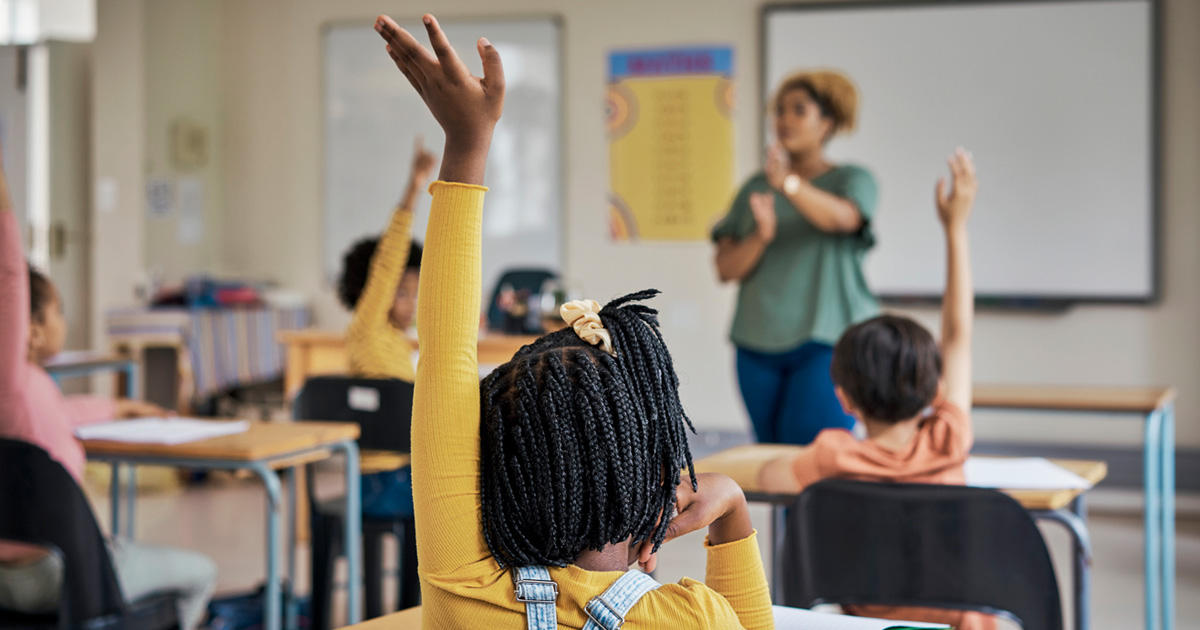 a child raising her hands in a classroom