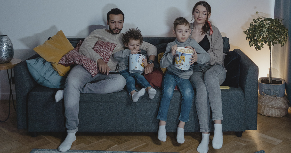 a family sitting on a couch eating popcorn